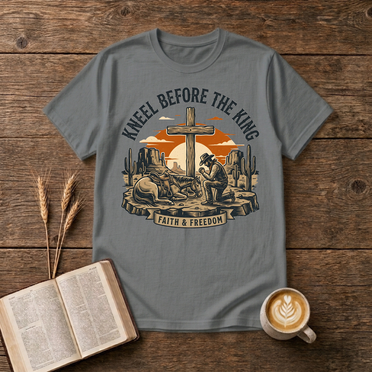 Cowboy kneeling in prayer beside his horse at a wooden cross in a desert sunset on a Graphite Heather unisex T-Shirt