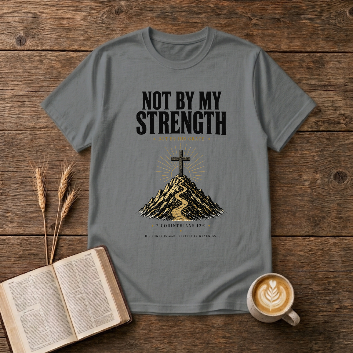 Distressed NOT BY MY STRENGTH lettering above a cross and mountain motif on a Graphite Heather unisex T-Shirt