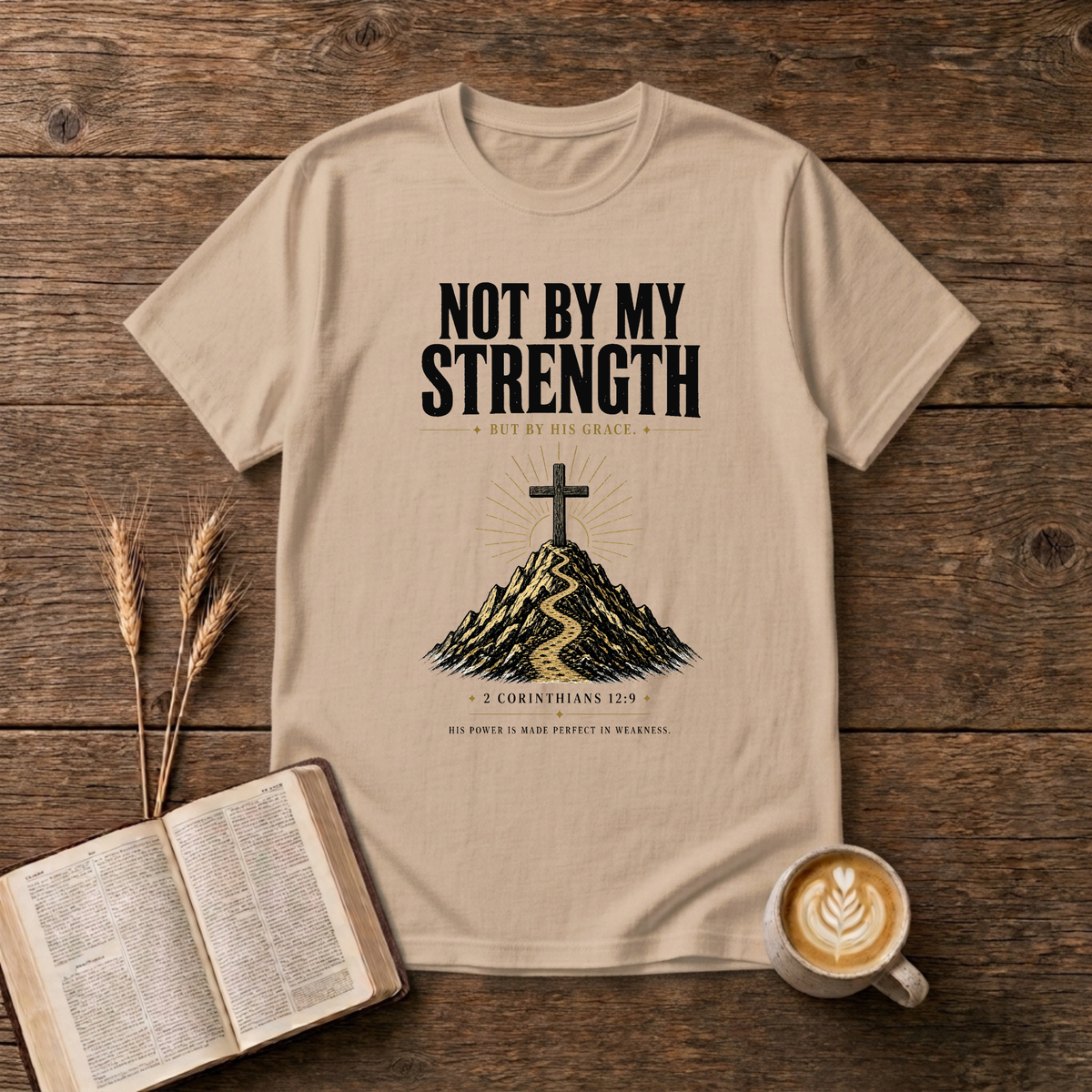 Distressed NOT BY MY STRENGTH lettering above a cross and mountain motif on a Natural unisex T-Shirt