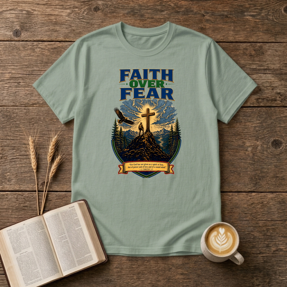 Faith Over Fear lettering over a mountain silhouette, pines and glowing cross on a Sage unisex T-Shirt