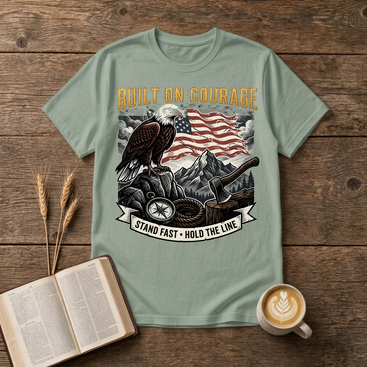 Built on Courage design of a stoic eagle before mountains with a faded American flag on a Sage unisex T-Shirt