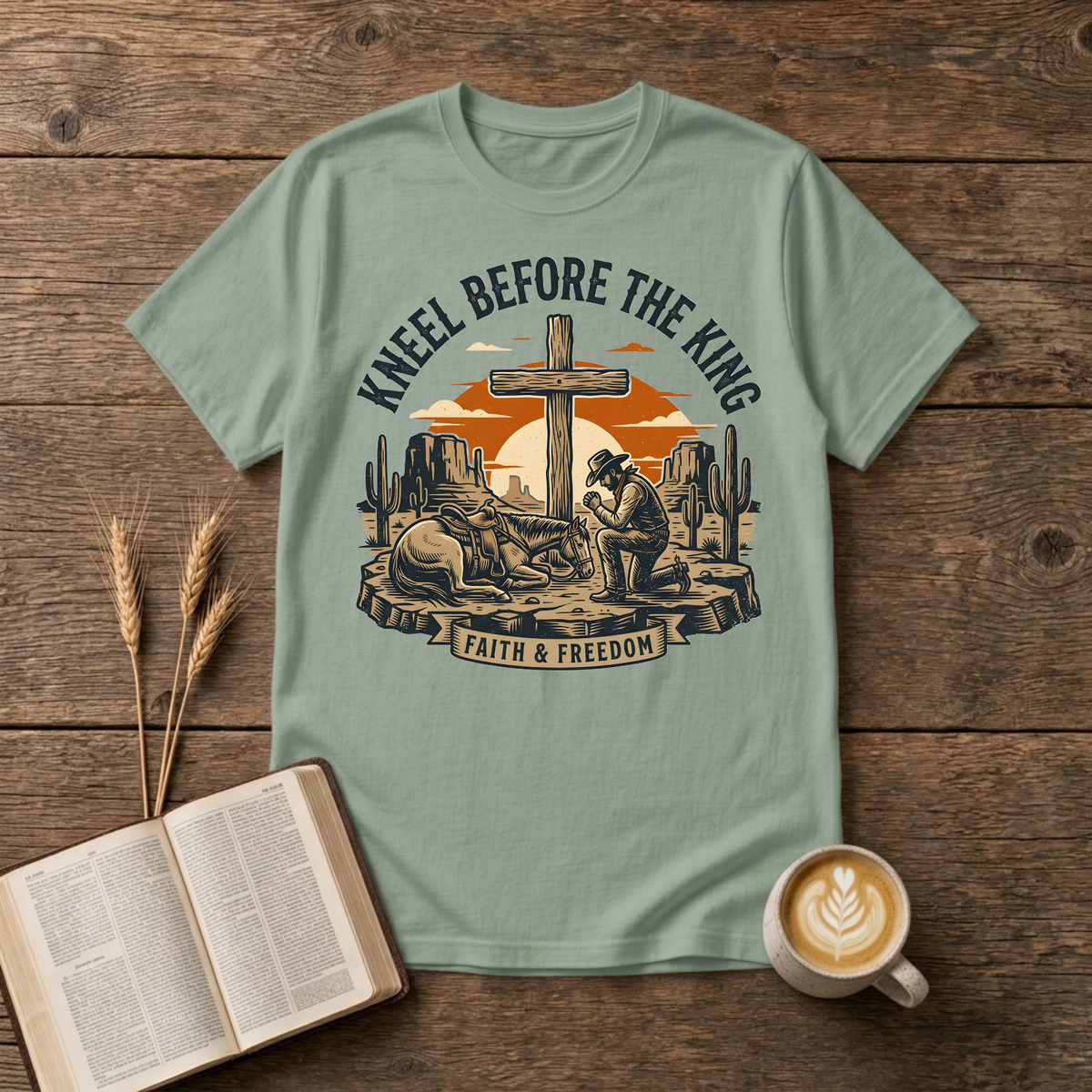 Cowboy kneeling in prayer beside his horse at a wooden cross in a desert sunset on a Sage unisex T-Shirt
