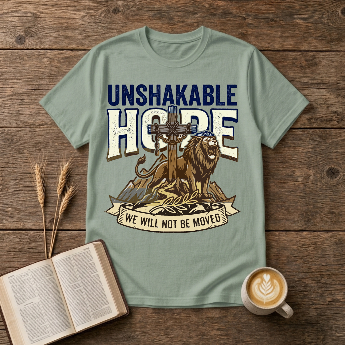 UNSHAKABLE HOPE lettering above a cross and lion illustration on a Sage unisex T-Shirt