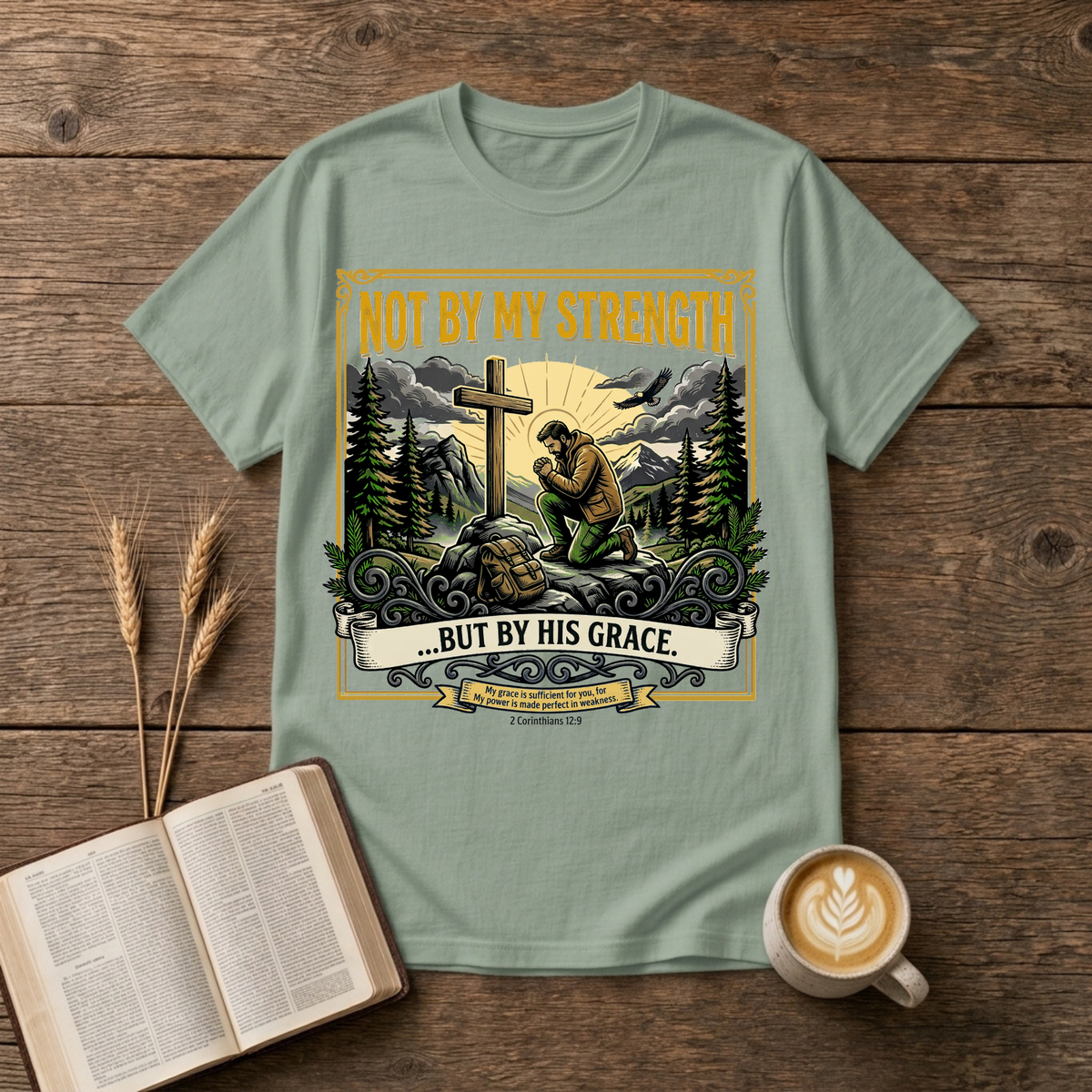 Figure kneeling at a cross in a forest clearing with Not By My Strength on a Sage unisex T-Shirt