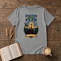 Faith Over Fear lettering over a mountain silhouette, pines and glowing cross on a Sport Grey unisex T-Shirt