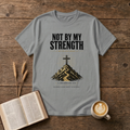 Distressed NOT BY MY STRENGTH lettering above a cross and mountain motif on a Sport Grey unisex T-Shirt