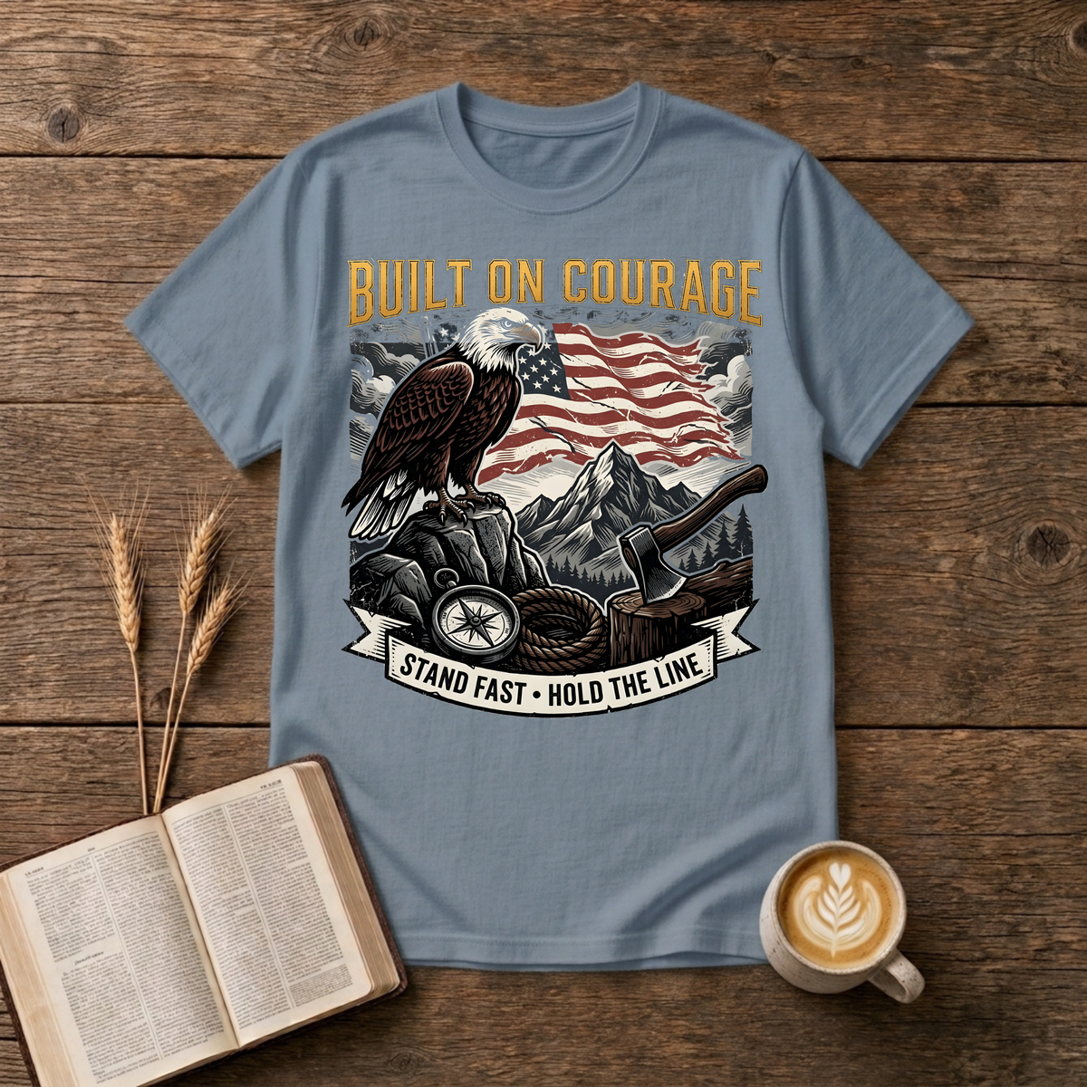 Built on Courage design of a stoic eagle before mountains with a faded American flag on a Stone Blue unisex T-Shirt