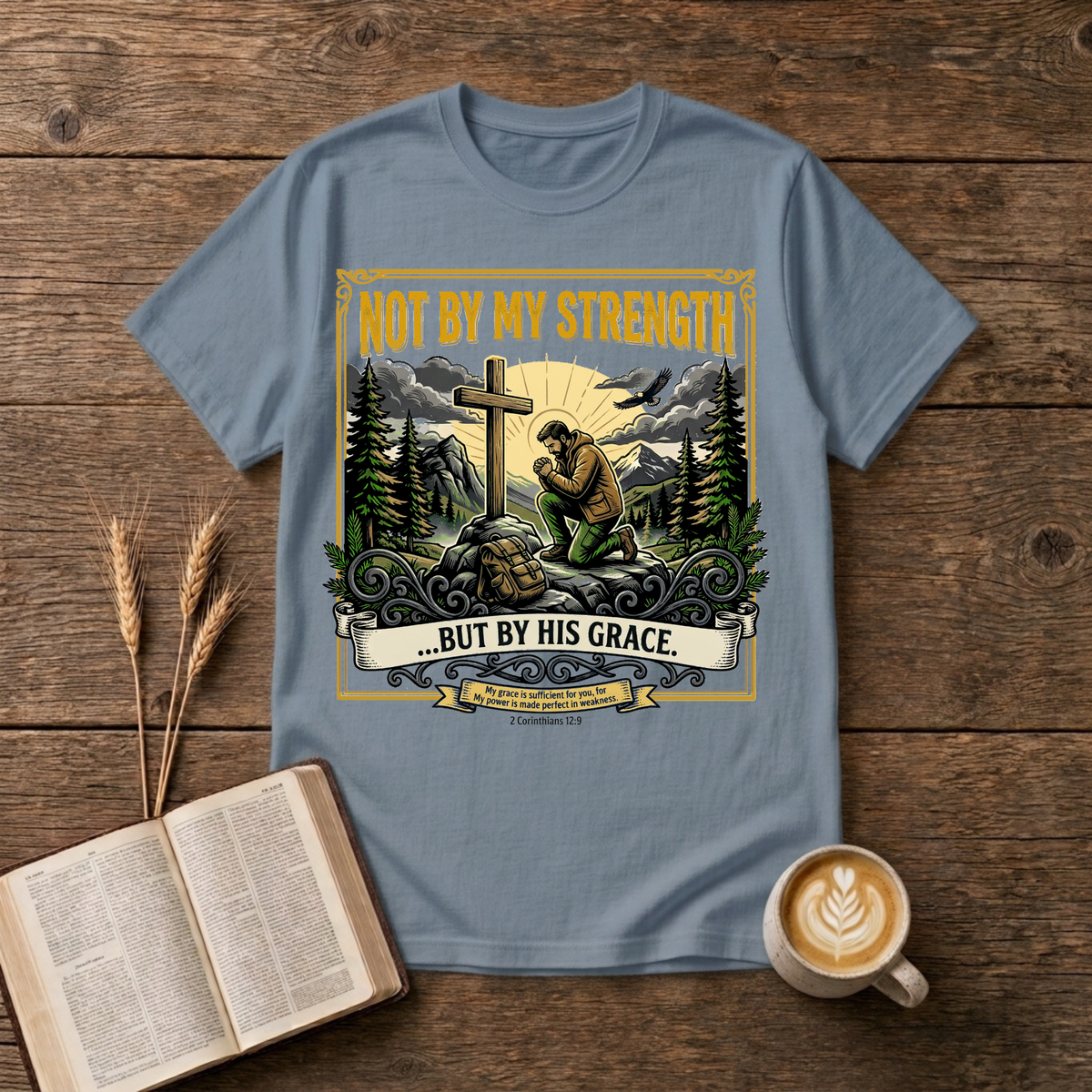 Figure kneeling at a cross in a forest clearing with Not By My Strength on a Stone Blue unisex T-Shirt
