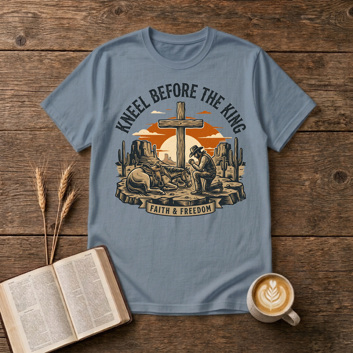 Cowboy kneeling in prayer beside his horse at a wooden cross in a desert sunset on a Stone Blue unisex T-Shirt