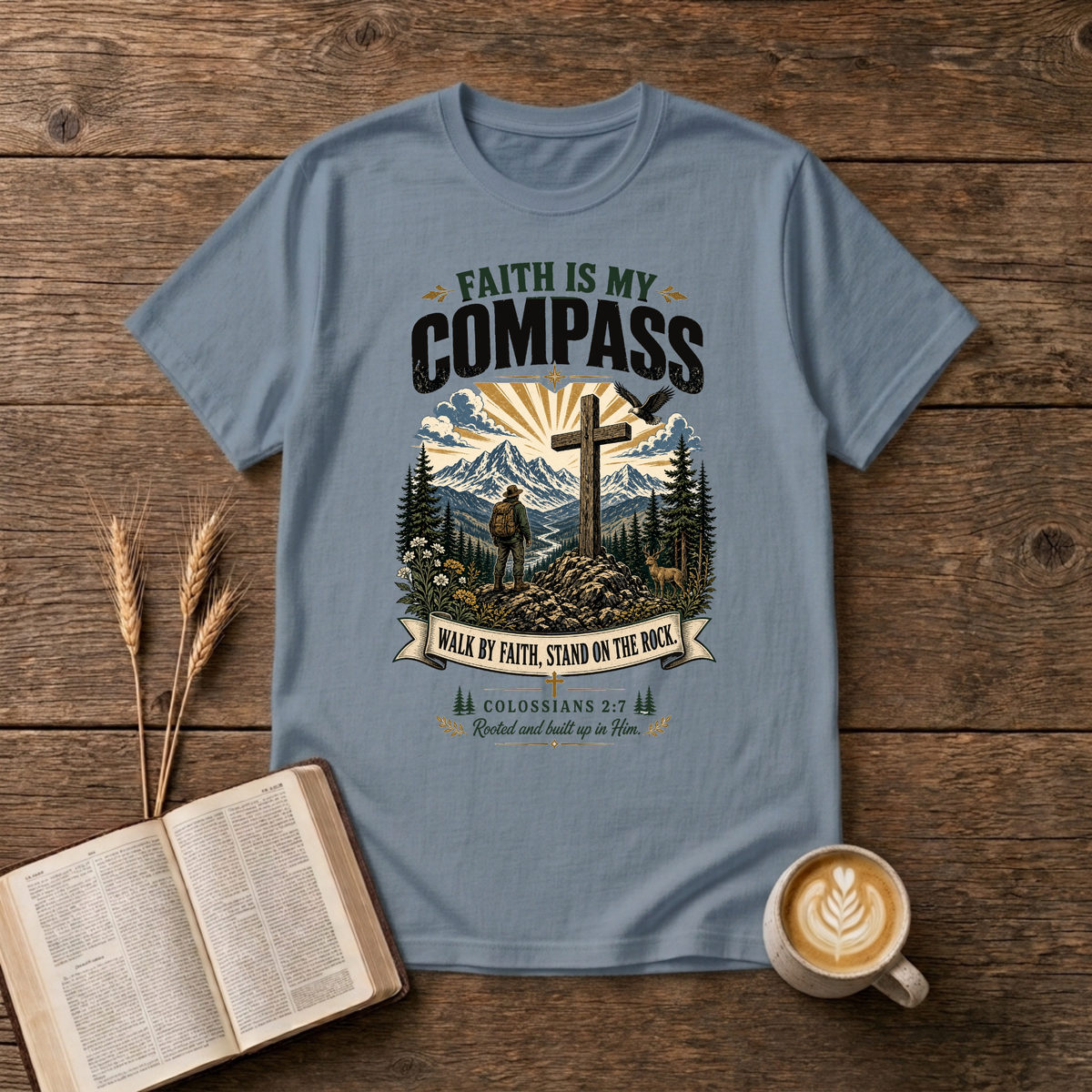 Faith Is My Compass lettering above a weathered cross amid pines and a rising sun on a Stone Blue unisex T-Shirt