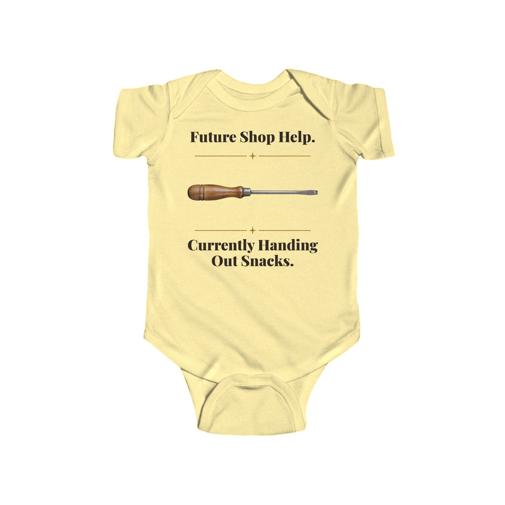 Future Shop Help baby bodysuit in Butter on a wood table with a knit blanket, wooden rattle and open Bible