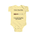 Future Shop Help baby bodysuit in Butter on a wood table with a knit blanket, wooden rattle and open Bible