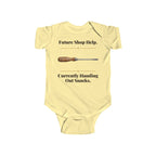 Future Shop Help baby bodysuit in Butter on a wood table with a knit blanket, wooden rattle and open Bible