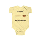 Grandma's Favorite Helper baby bodysuit in Butter on a wood table with a knit blanket, wooden rattle and open Bible
