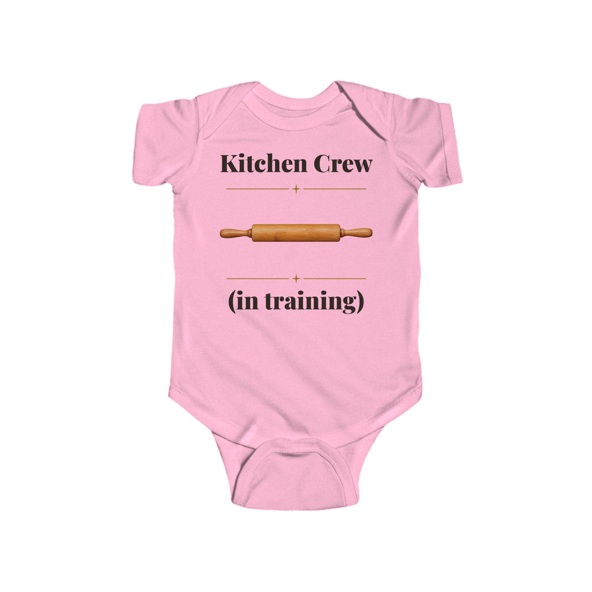 Kitchen Crew in Training baby bodysuit in Pink on a wood table with a knit blanket, wooden rattle and open Bible