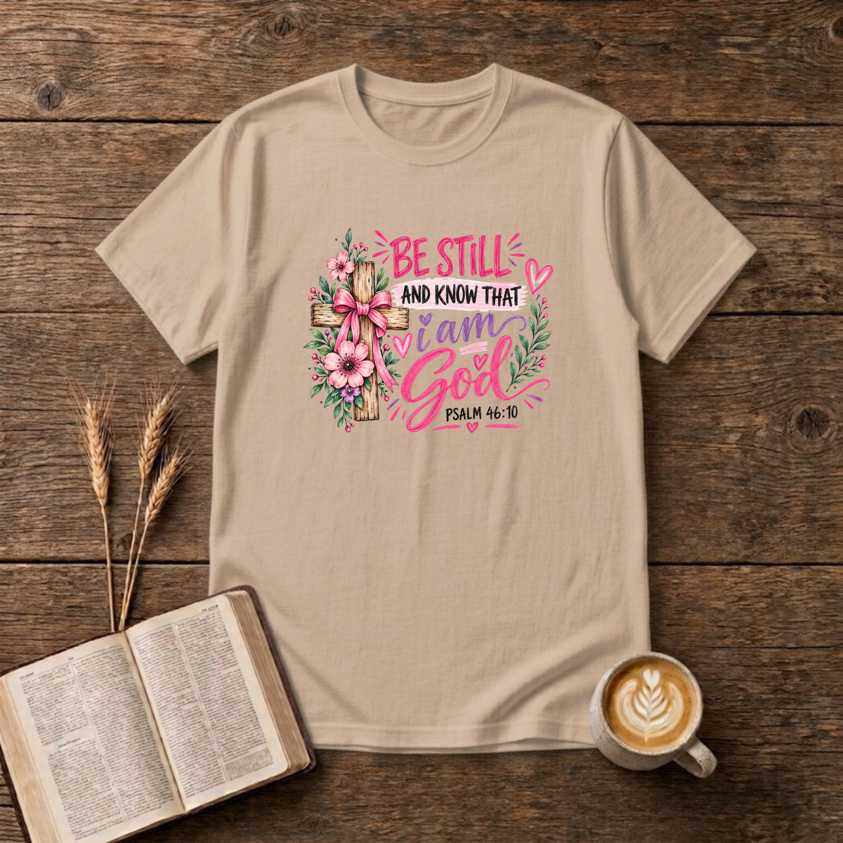 Be Still and Know That I Am God Psalm 46:10 design with a wooden cross wrapped in a pink bow and pink and purple flowers on a Natural unisex T-Shirt