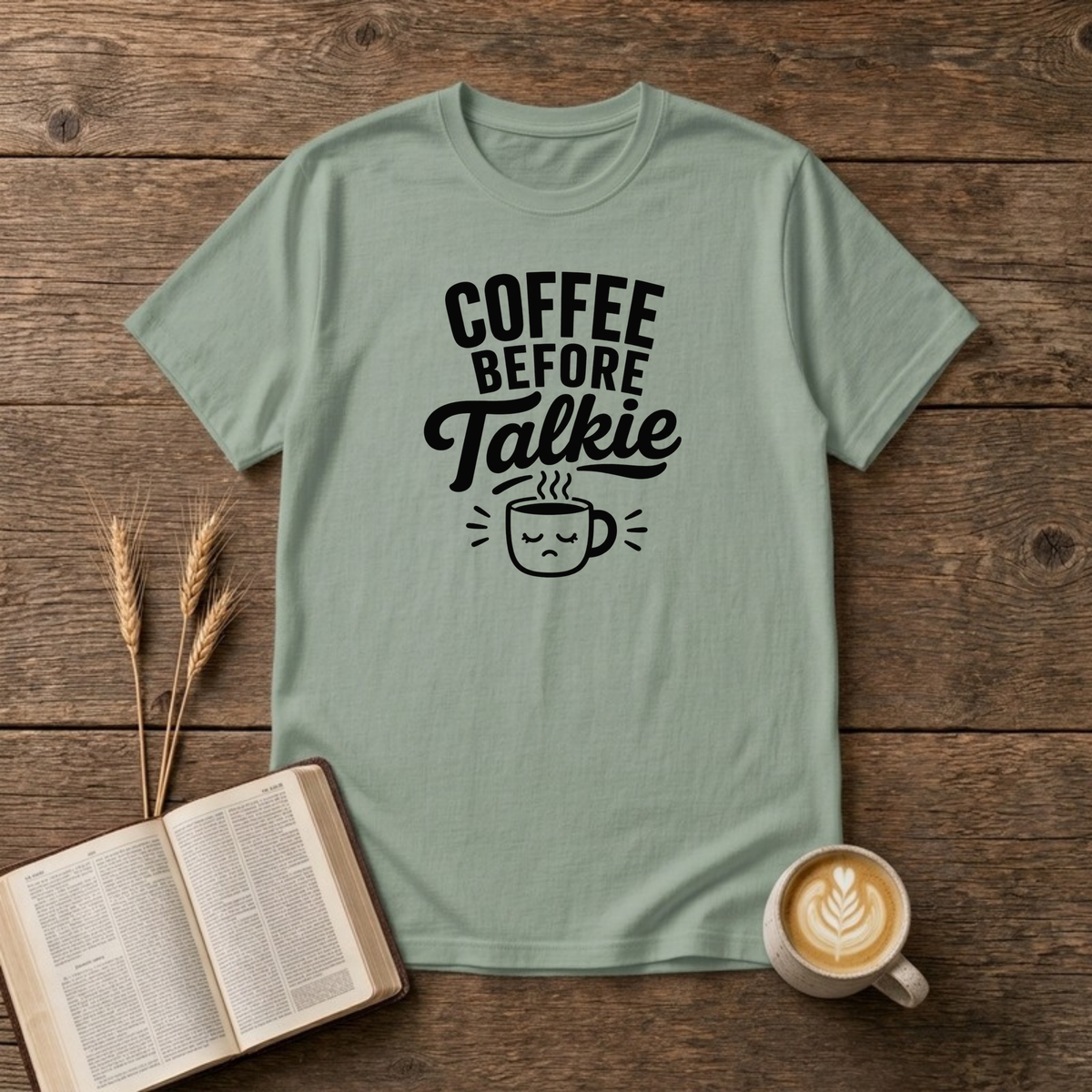 Coffee Before Talkie design with black lettering above a sleepy frowning coffee cup on a Sage unisex T-Shirt