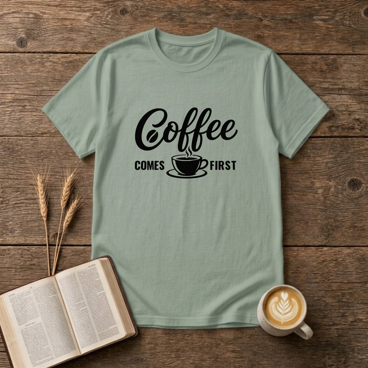 Coffee Comes First design with black script and block lettering around a steaming coffee cup on a Sage unisex T-Shirt