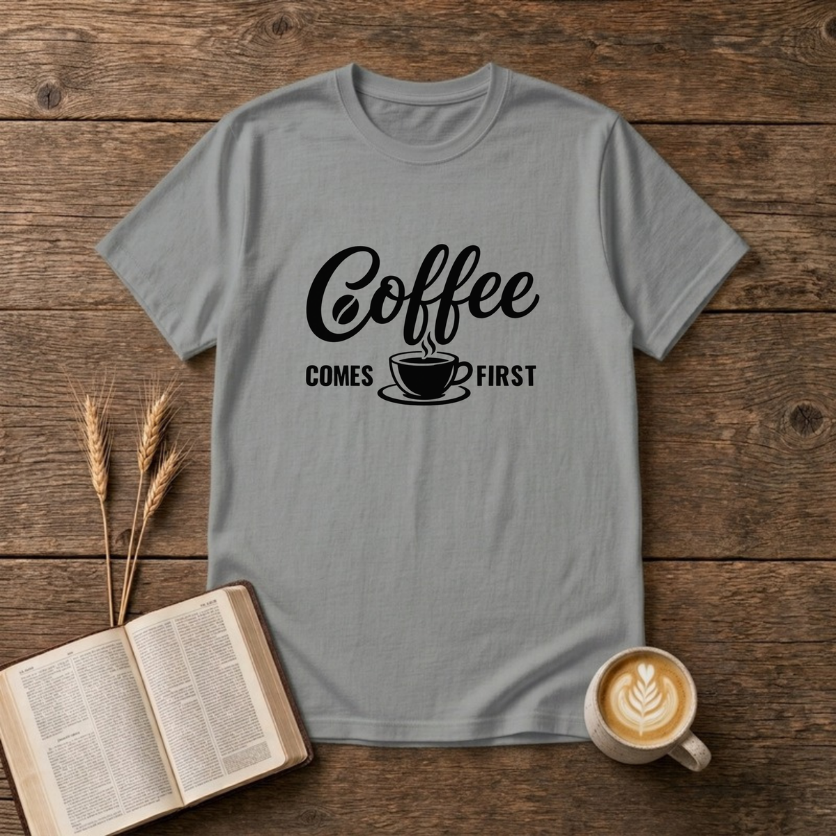 Coffee Comes First design with black script and block lettering around a steaming coffee cup on a Sport Grey unisex T-Shirt