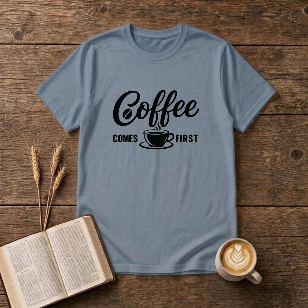 Coffee Comes First design with black script and block lettering around a steaming coffee cup on a Stone Blue unisex T-Shirt