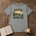Faith Builds Roads Through Impossible Places design with dark green and orange lettering around a winding mountain road, evergreen forest, lake and sunrise on a Sport Grey unisex T-Shirt