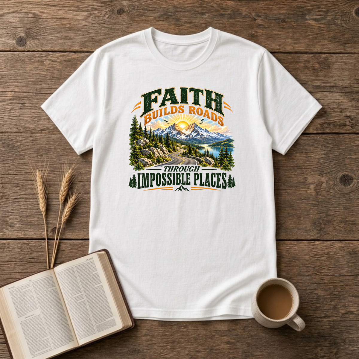 Faith Builds Roads Through Impossible Places design with dark green and orange lettering around a winding mountain road, evergreen forest, lake and sunrise on a White unisex T-Shirt