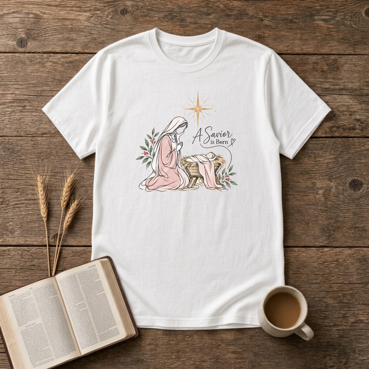 A Savior Is Born watercolor nativity design of Mary kneeling beside baby Jesus in the manger under a gold star on a White unisex T-Shirt