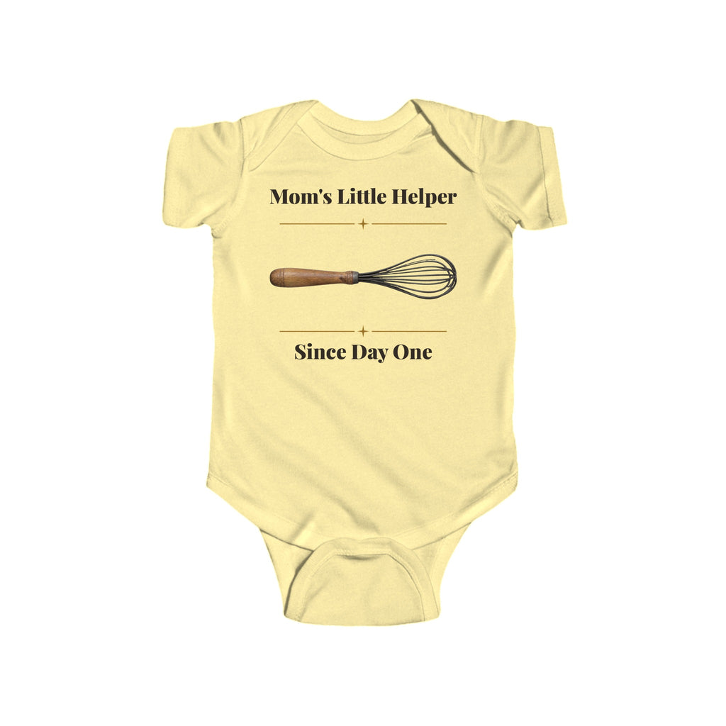 Mom's Little Helper Since Day One baby bodysuit in Butter on a wood table with a knit blanket, wooden rattle and open Bible