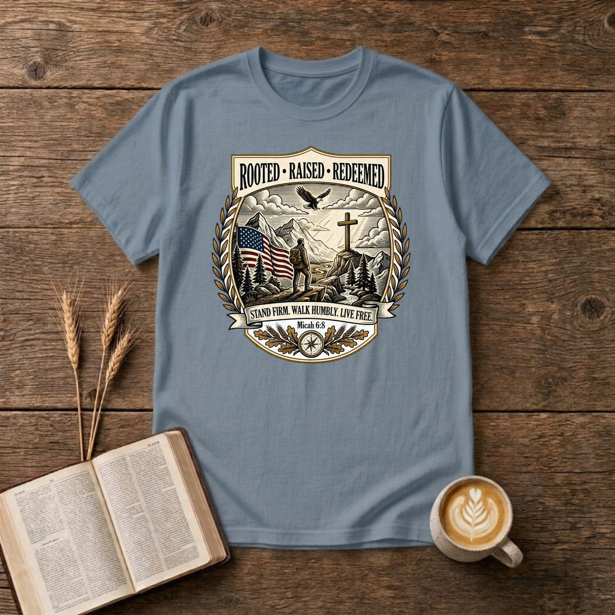 Rooted. Raised. Redeemed. crest badge with a hiker, cross, American flag, eagle and laurel frame on a Stone Blue unisex T-shirt