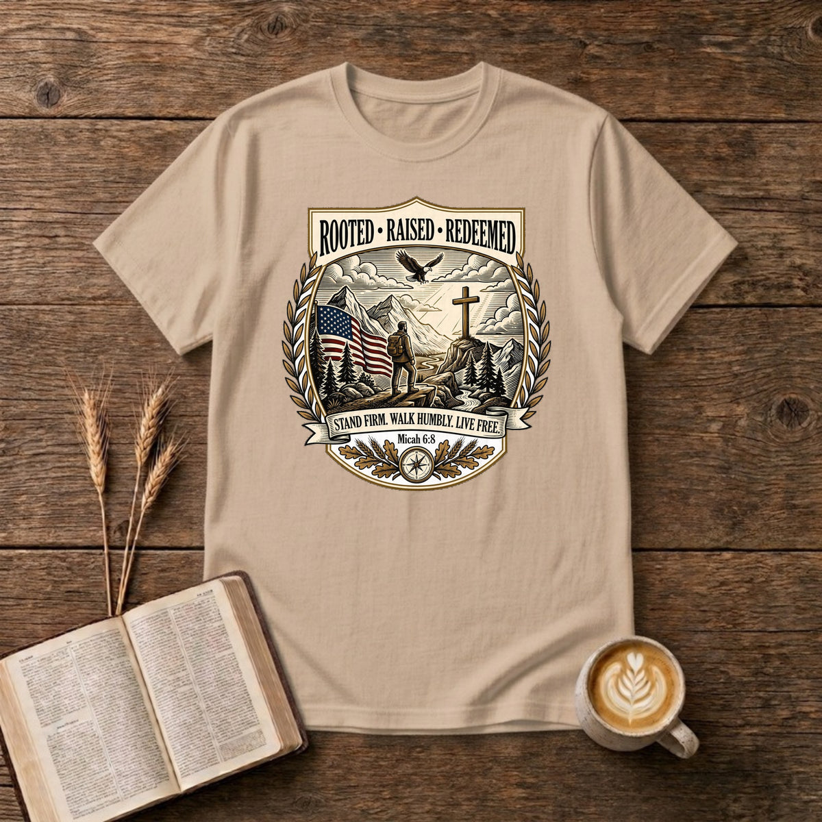 Rooted. Raised. Redeemed. crest badge with a hiker, cross, American flag, eagle and laurel frame on a Natural unisex T-shirt