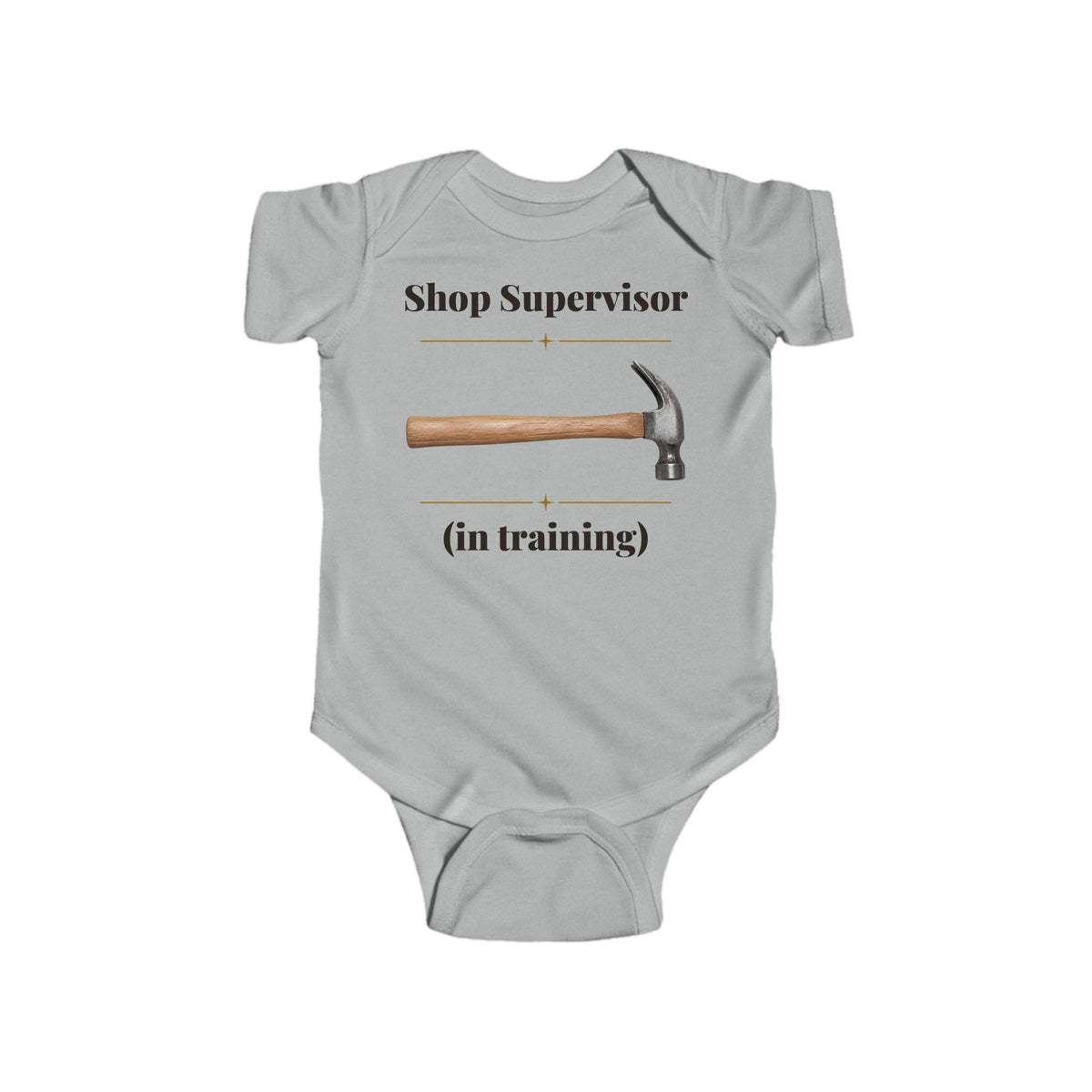 Shop Supervisor in Training baby bodysuit in Heather on a wood table with a knit blanket, wooden rattle and open Bible